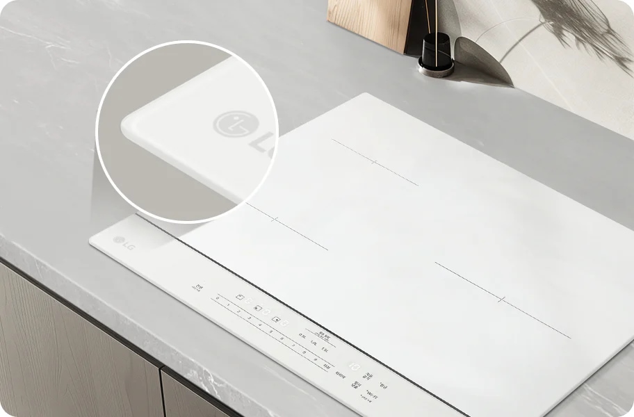 이미지는 LG 브랜드의 인덕션 쿡탑을 보여주고 있습니다. 쿡탑은 세련된 디자인으로, 주방의 현대적인 분위기와 잘 어울립니다. 표면은 매끈하고 깨끗한 화이트 색상이며, 상단에는 조리 기구를 놓을 수 있는 공간이 확보되어 있습니다. 아래쪽에는 다양한 조작 버튼과 표시가 있어 쉽게 사용할 수 있도록 설계되어 있습니다. 전체적으로 고급스러운 느낌을 주며, 실용성과 미적 요소를 동시에 갖춘 주방 기기입니다.