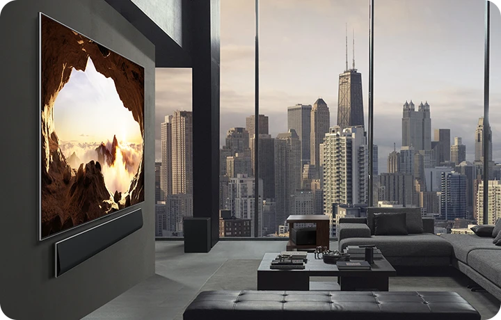 도시 풍경이 보이는 넓은 거실. LG OLED TV는 LG 사운드바가 있는 벽에 장착되어 있습니다. 측면에서 보면 TV의 원월 디자인과 슬림한 베젤이 벽과 공간과 잘 어우러집니다. 제로 커넥트 박스는 보이지만 숨겨져 있습니다.