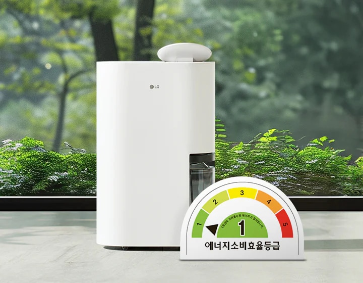 LG 휘센 오브제컬렉션 제습기가 실내에 놓여 있으며, 제품은 매끄러운 흰색 외관을 가지고 있습니다. 제습기 옆에는 투명한 물통이 보입니다. 이미지 하단에는 에너지 소비 효율 등급을 나타내는 반원형 그래프가 있으며, 에너지소비효율등급이라는 문구와 함께 1등급이 표시되어 있습니다. 배경에는 큰 창문을 통해 녹색 식물이 보입니다.