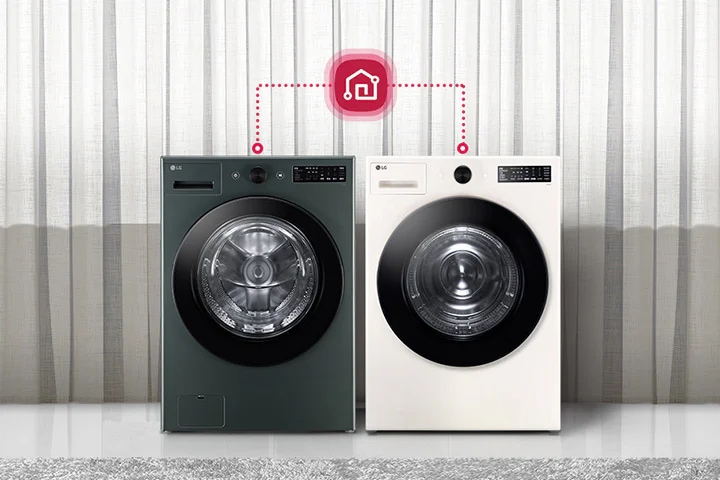 두 대의 LG 세탁기가 나란히 놓여 있으며, 각각의 세탁기 위에는 제어 패널이 있습니다. 세탁기 위에는 스마트 홈 연결을 나타내는 아이콘이 있으며, 점선으로 두 세탁기와 연결되어 있습니다. 배경에는 커튼이 드리워져 있고, 세탁기 옆에는 의자와 테이블이 놓여 있습니다. 테이블 위에는 장식용 꽃병이 있습니다.